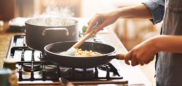 Image of person cooking with pot and pan on a stovetop