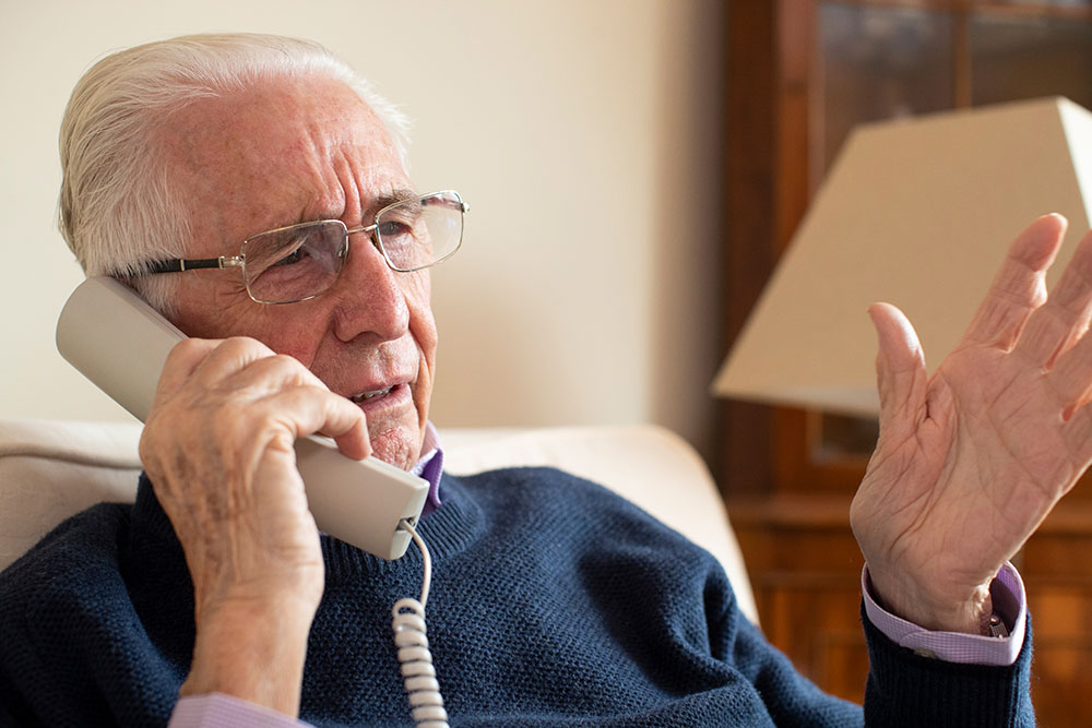 Elderly man talks on corded phone