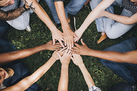 Group sits in a circle with their hands in